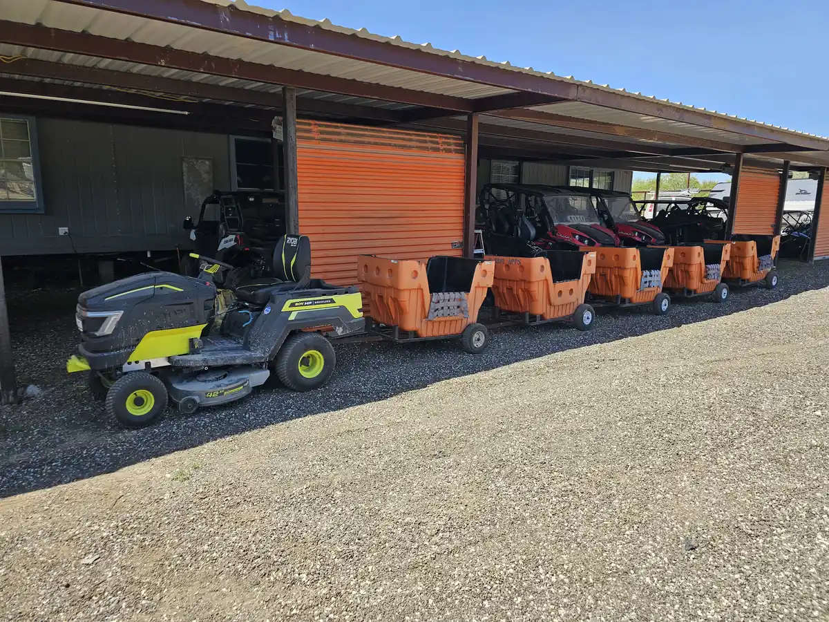 The five train carts parked under the covered area beside the UTV rental fleet
